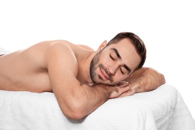 Handsome man relaxing on massage table against white background. Spa service