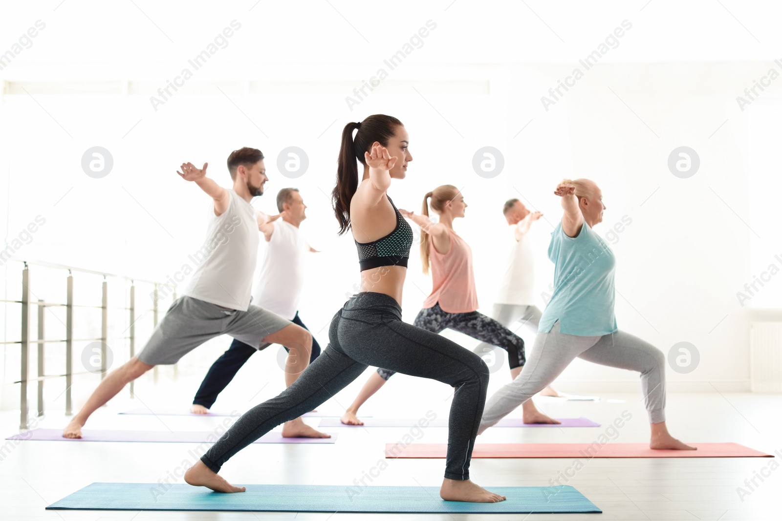 Photo of Group of people in sportswear practicing yoga indoors