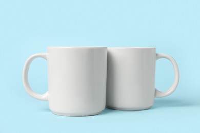 Photo of Two white ceramic mugs on light blue background