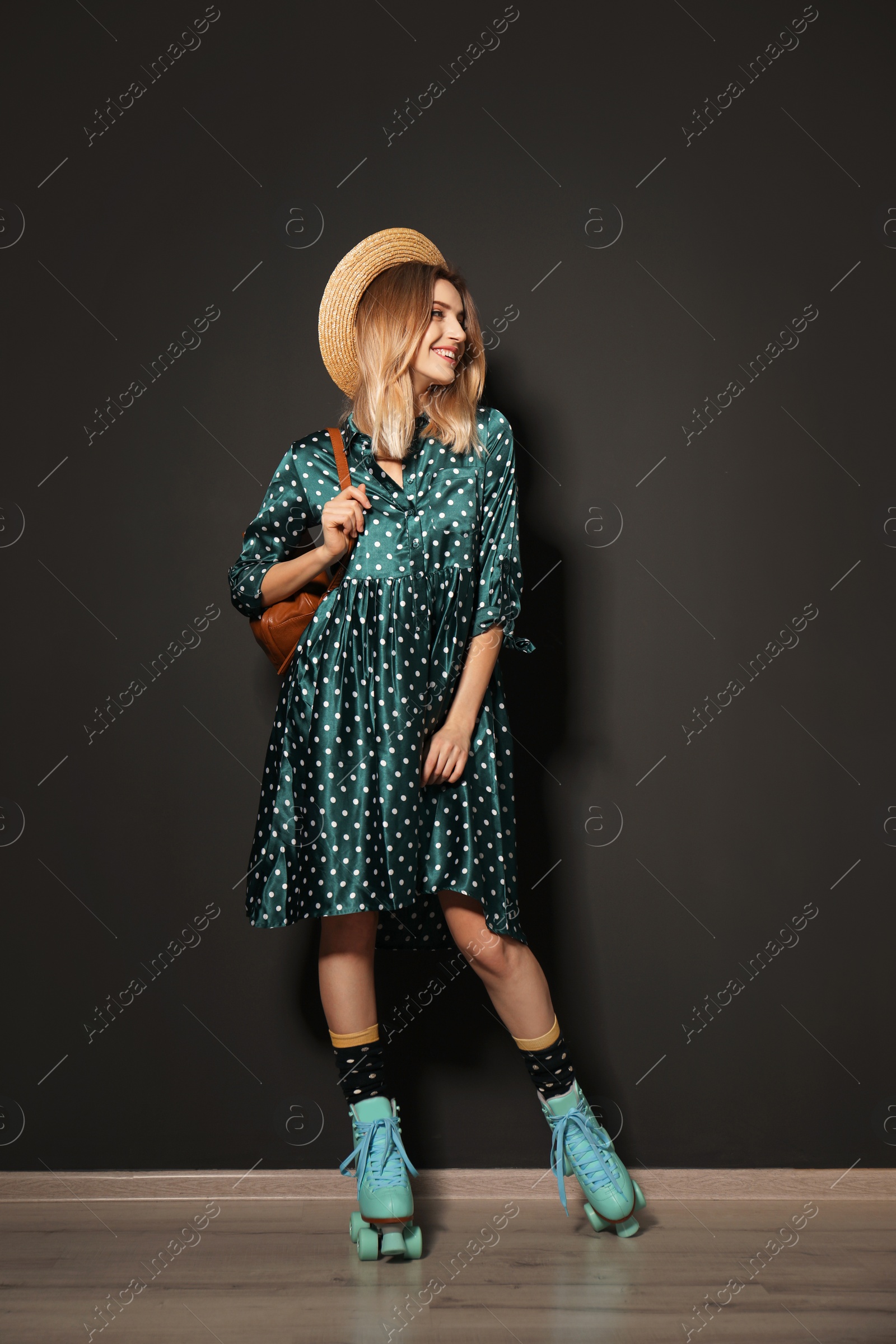 Photo of Young woman with retro roller skates against black wall