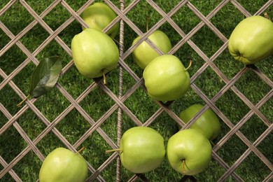Fresh green apples on rattan grid, top view