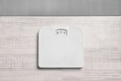 Photo of Bathroom scales and yoga mat on wooden background, top view. Weight loss concept