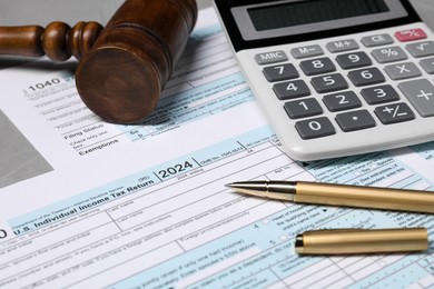 Tax return forms, gavel, calculator and pen on grey table, closeup