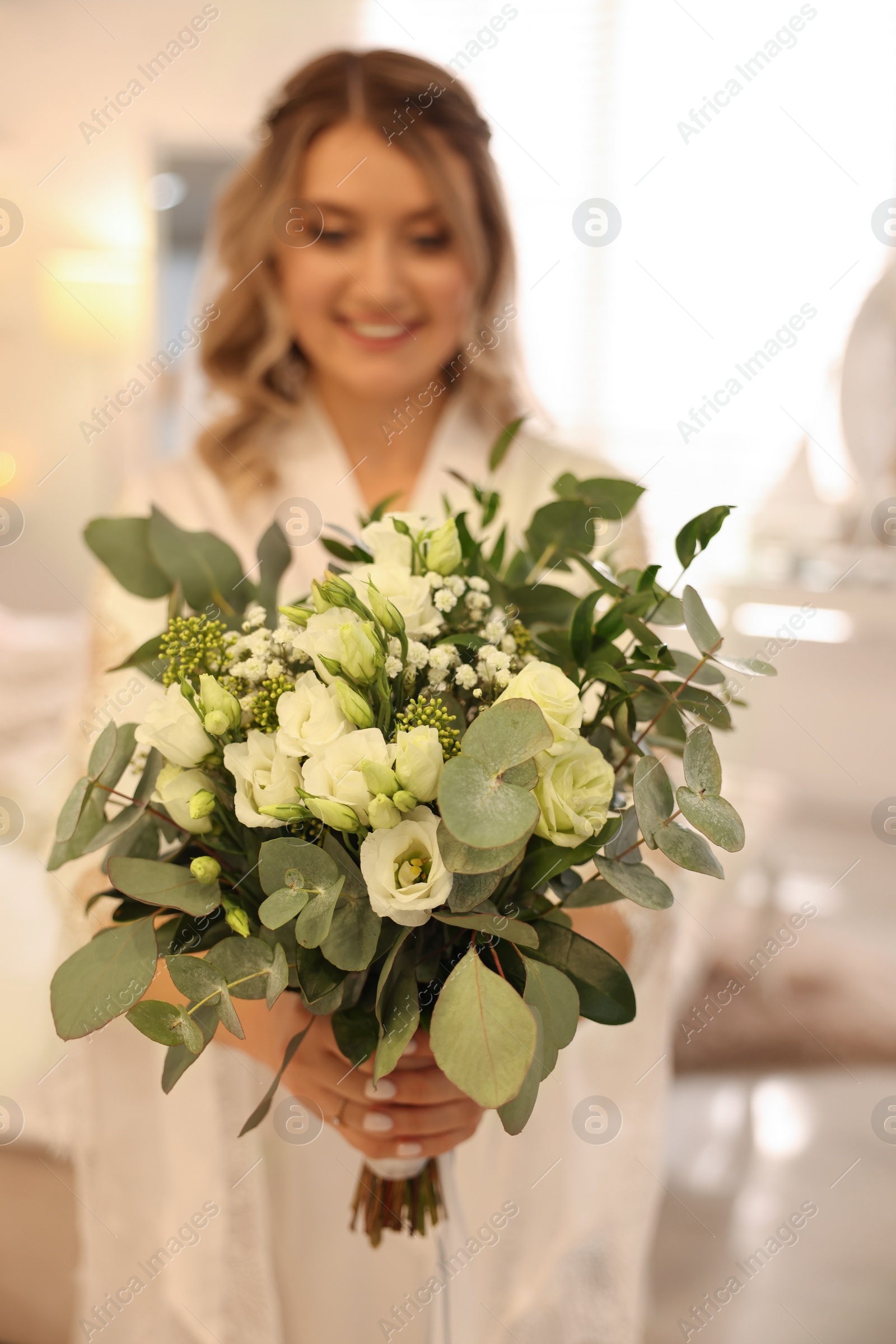 Photo of Happy bride with beautiful bouquet at home, focus on flowers. Wedding day