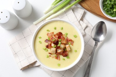 Photo of Tasty potato soup with bacon in bowl served on white table, flat lay