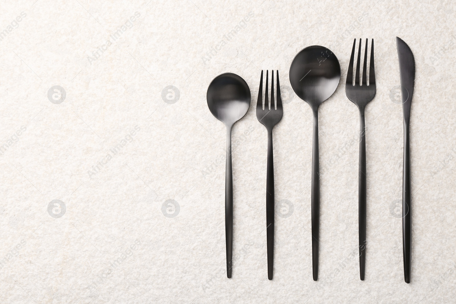 Photo of Stylish cutlery set on beige textured table, flat lay. Space for text