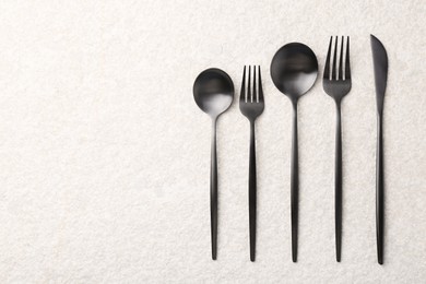 Stylish cutlery set on beige textured table, flat lay. Space for text