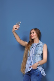 Photo of Attractive young woman taking selfie on color background