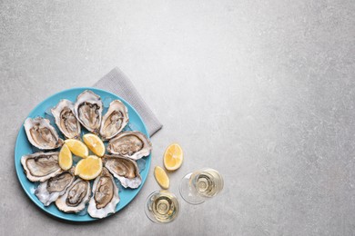 Photo of Fresh oysters with lemon and glasses of champagne on grey table, flat lay. Space for text
