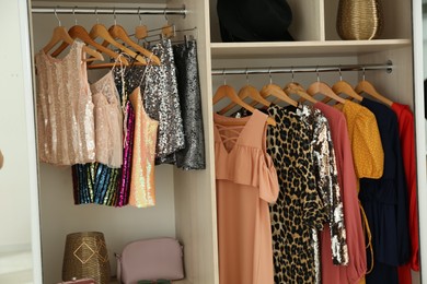 Photo of Different stylish women's clothes on hangers in wardrobe
