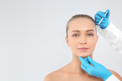 Young woman getting facial injection and space for text on white background. Cosmetic surgery concept