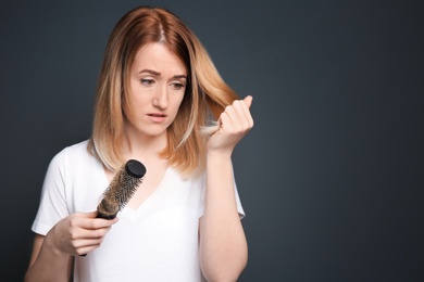 Young woman with hair loss problem on gray background