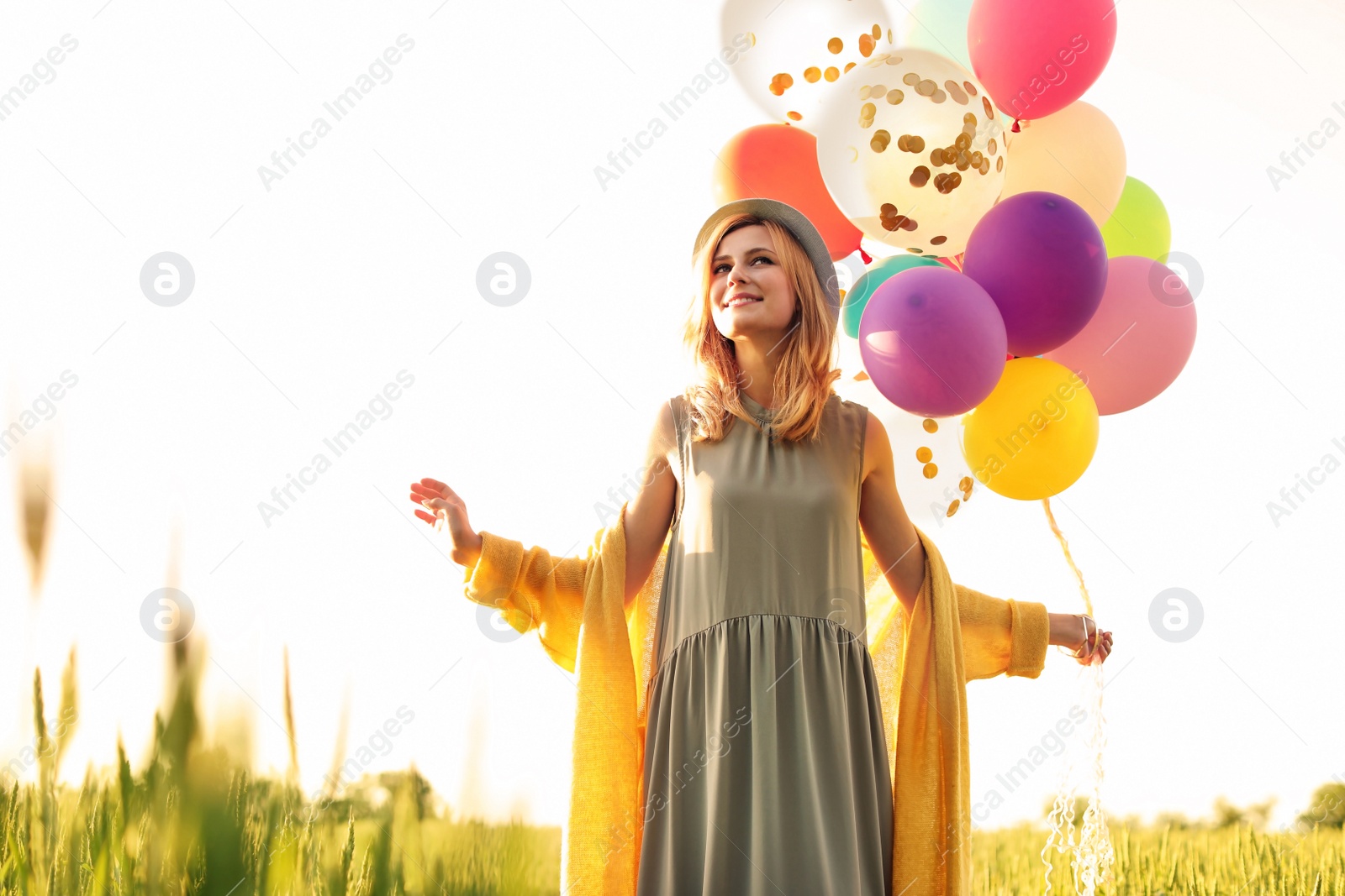 Photo of Young woman with colorful balloons outdoors on sunny day