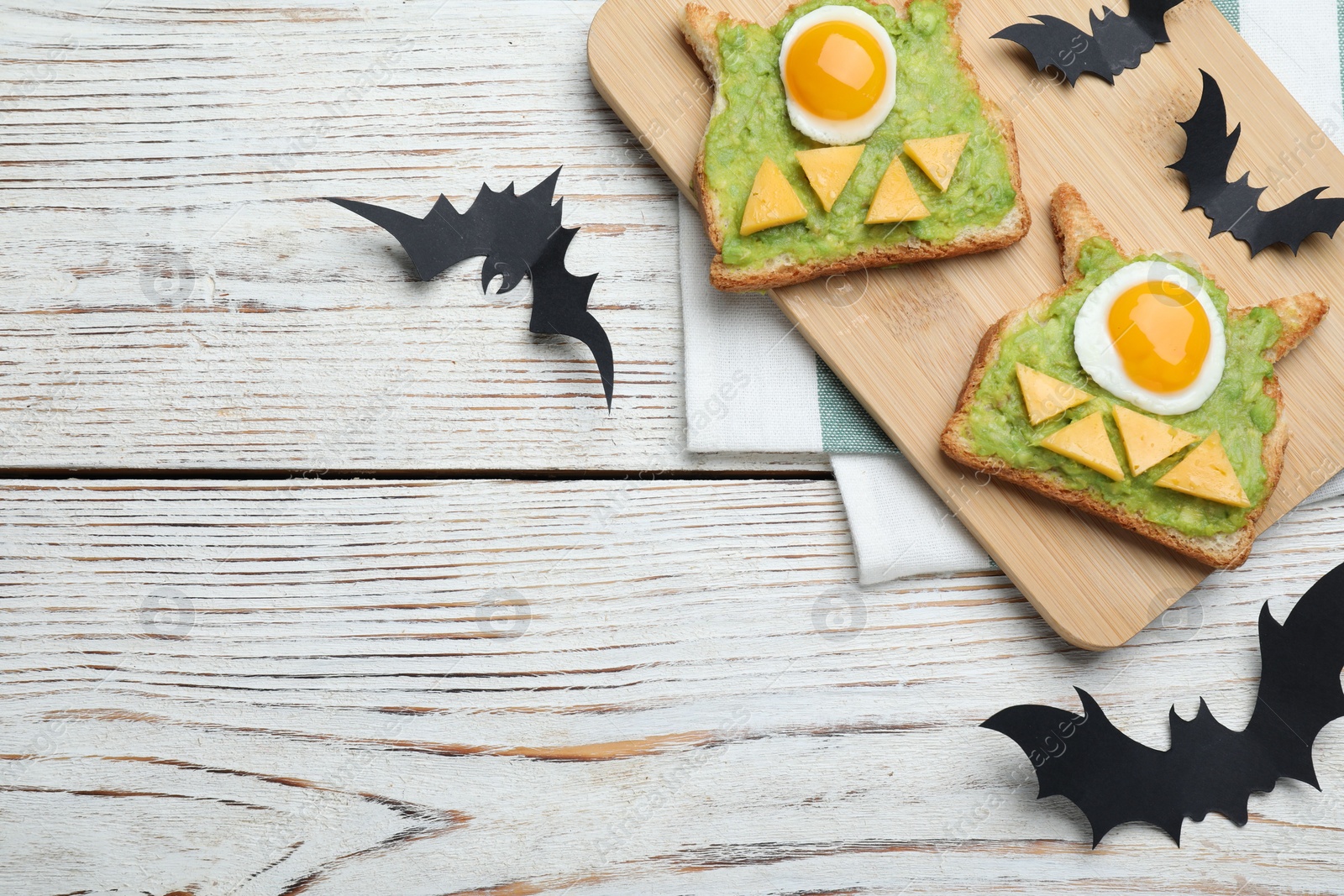 Photo of Halloween themed breakfast served on white wooden table, flat lay and space for text. Tasty sandwiches with fried eggs