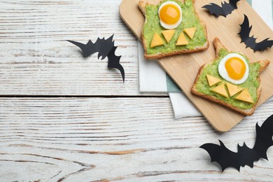 Halloween themed breakfast served on white wooden table, flat lay and space for text. Tasty sandwiches with fried eggs