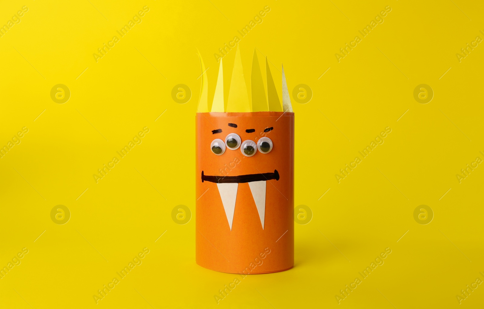 Photo of Funny orange monster on yellow background. Halloween decoration