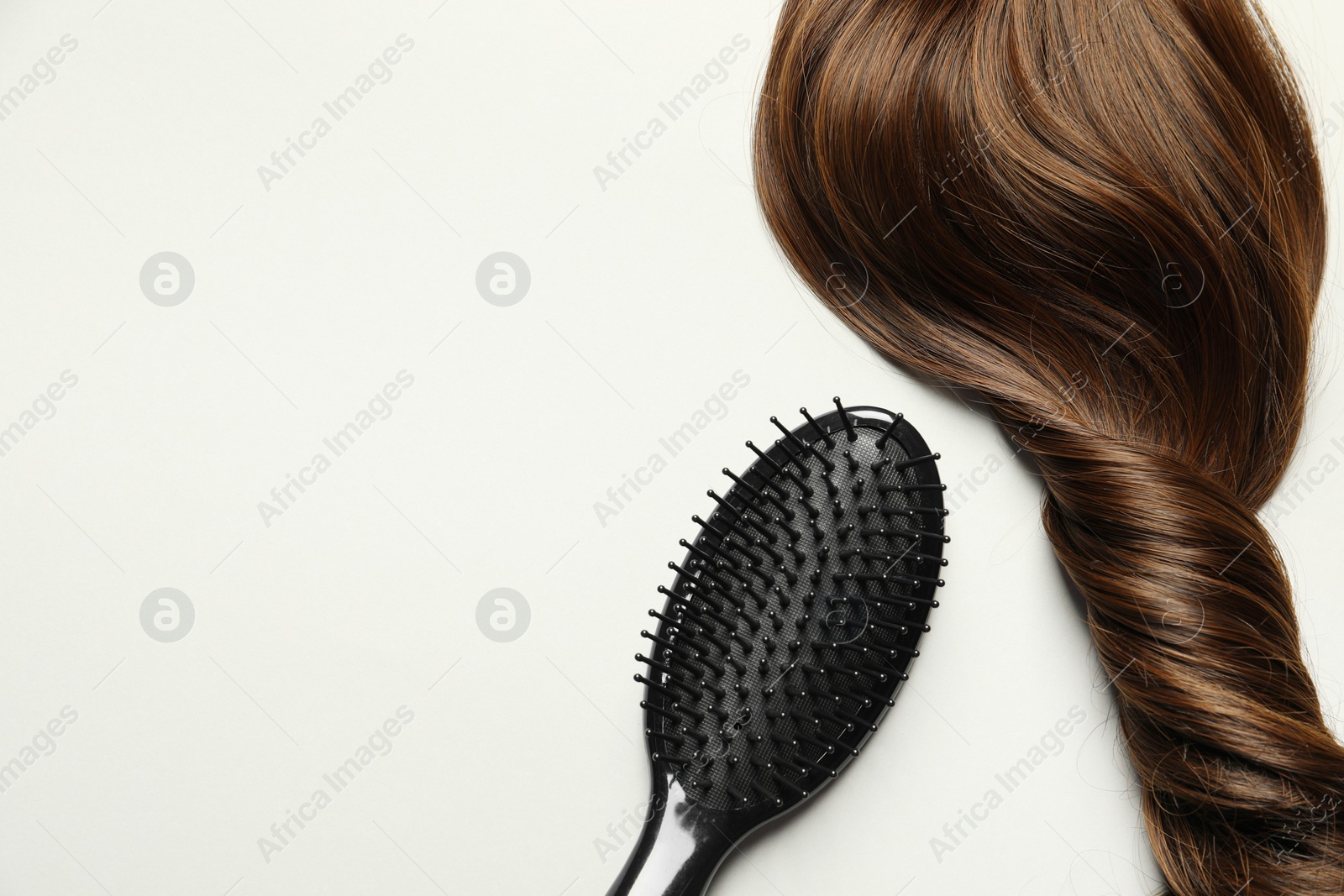 Photo of Stylish brush with brown hair strand on light grey background, top view. Space for text