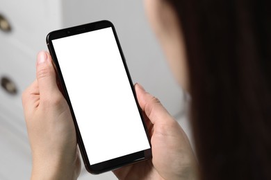 Photo of Woman holding smartphone with blank screen indoors, closeup. Mockup for design