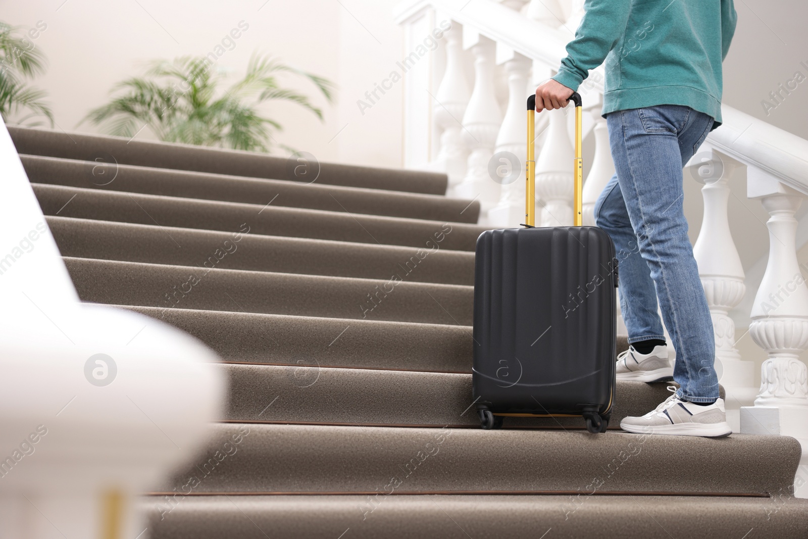 Photo of Man with suitcase going up stairs in hotel, closeup