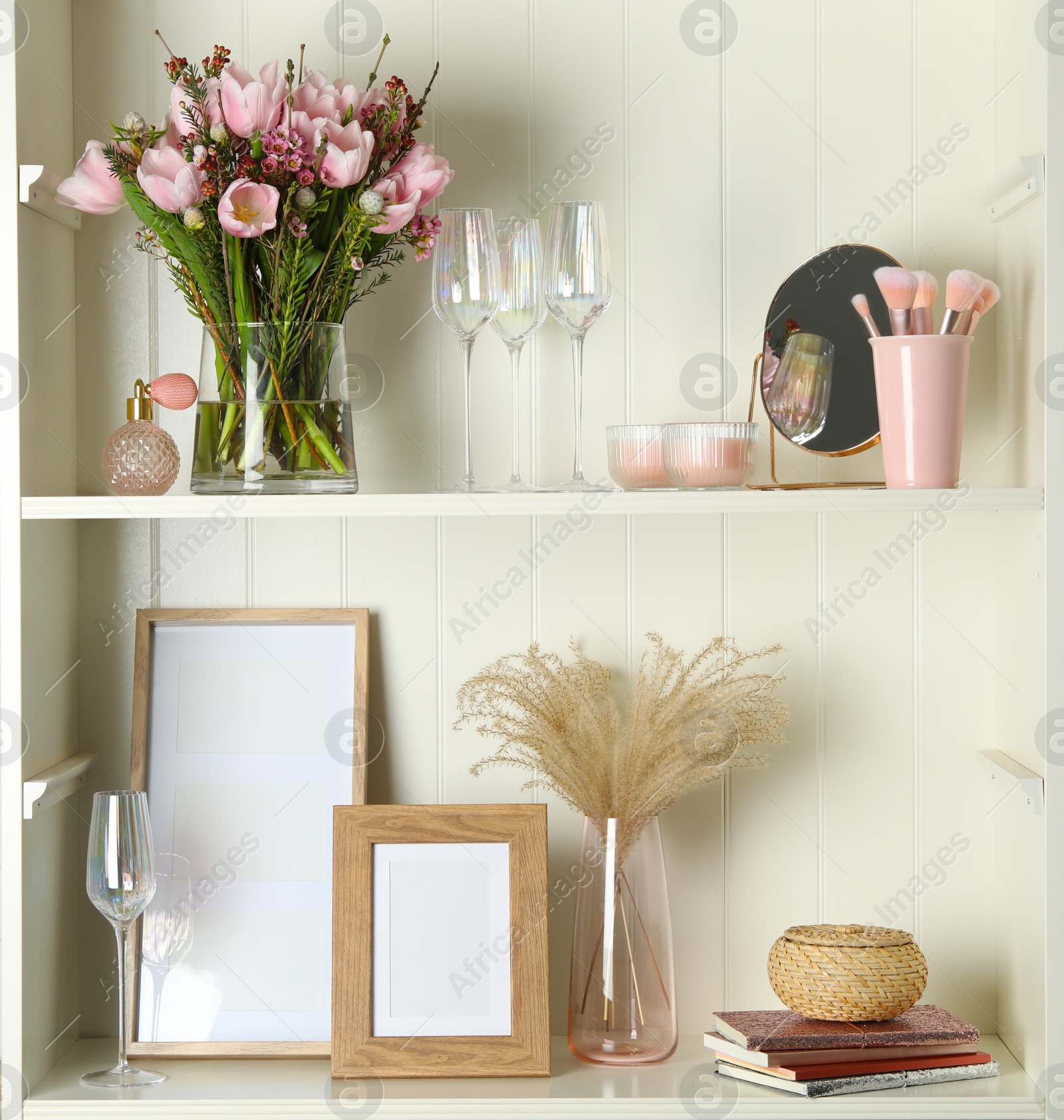 Photo of White shelving unit with glassware and different decorative elements