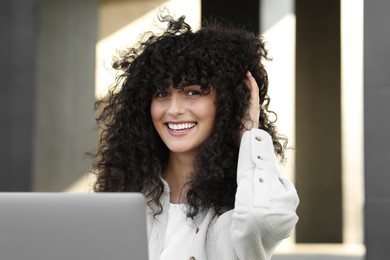 Happy young woman using modern laptop outdoors