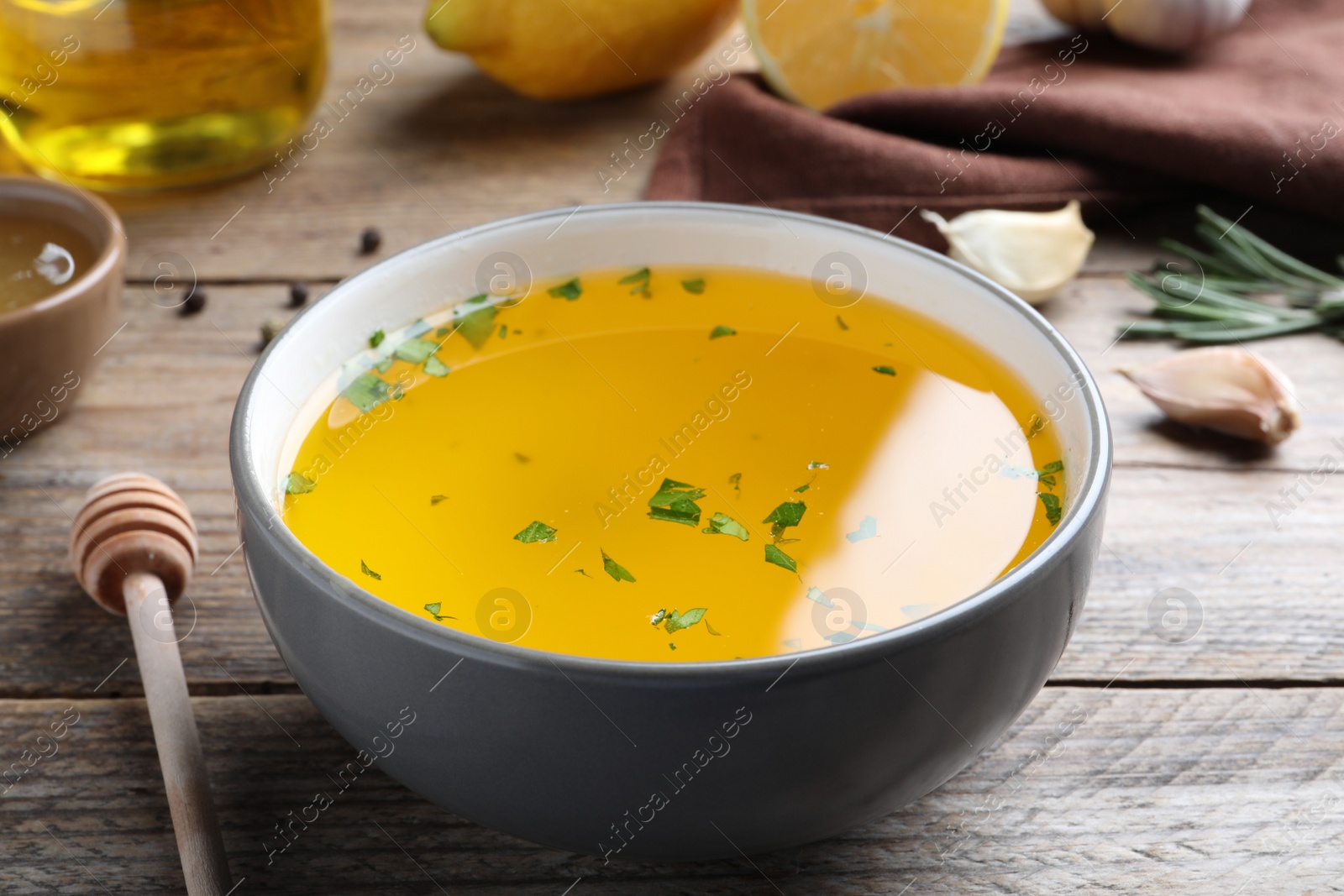 Photo of Bowl with lemon sauce on wooden table, closeup. Delicious salad dressing