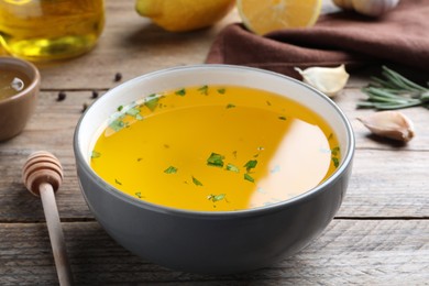 Bowl with lemon sauce on wooden table, closeup. Delicious salad dressing