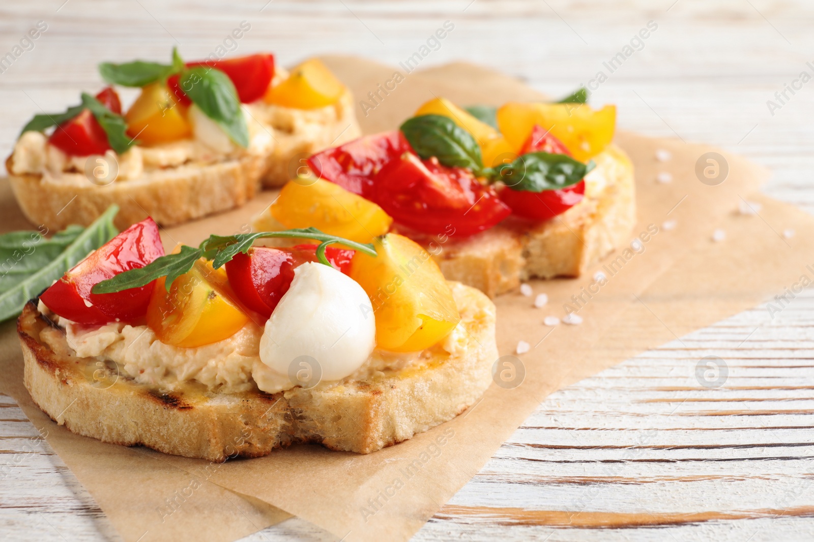 Photo of Delicious tomato bruschettas on white wooden background, closeup