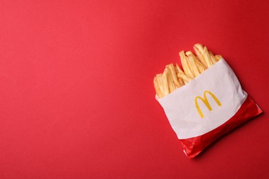 Photo of MYKOLAIV, UKRAINE - AUGUST 12, 2021: Small portion of McDonald's French fries on red background, top view. Space for text