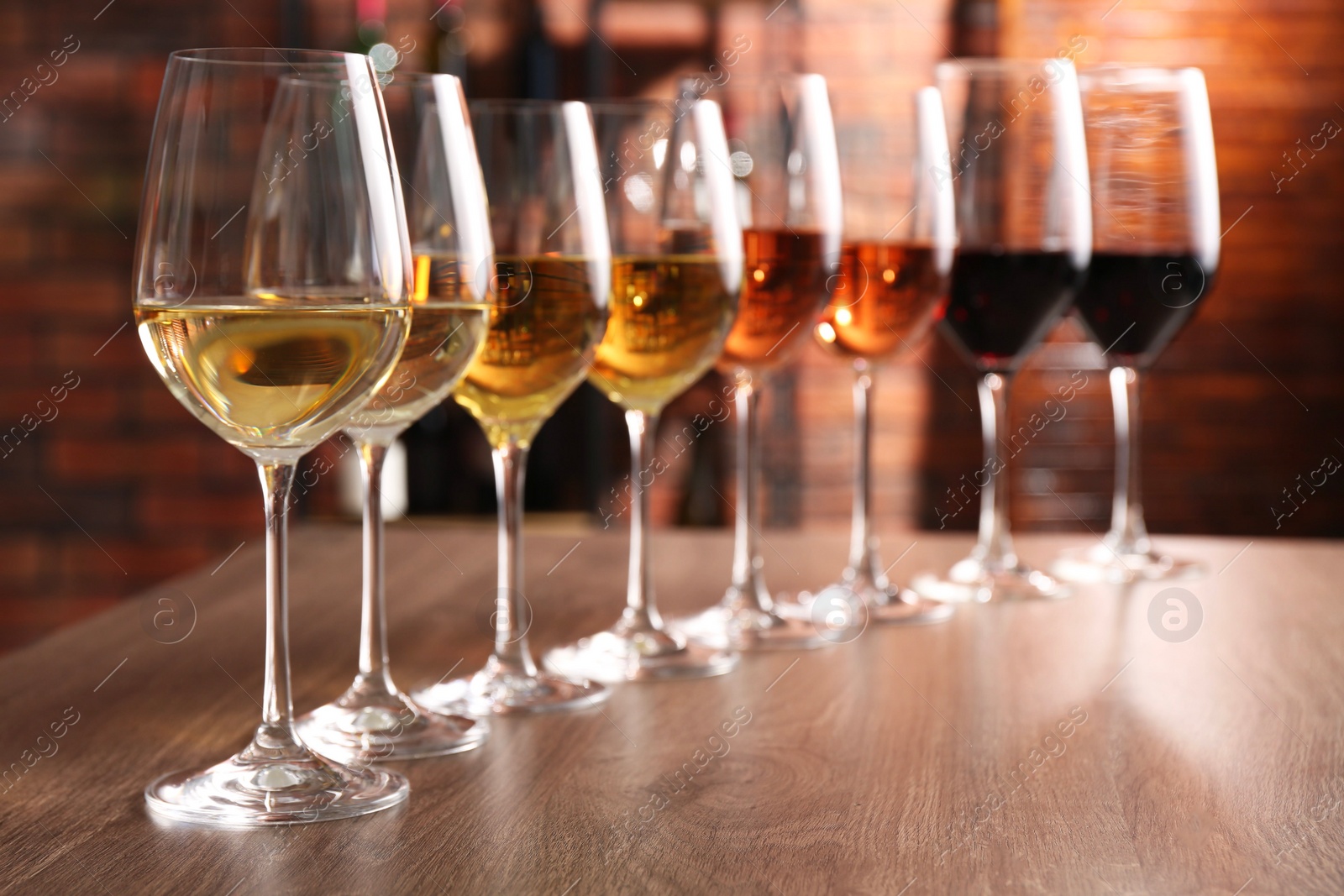 Photo of Different tasty wines in glasses on wooden table