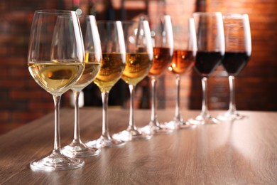 Different tasty wines in glasses on wooden table