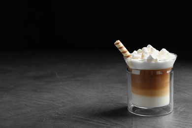 Photo of Glass with delicious coffee drink on grey table against black background. Space for text