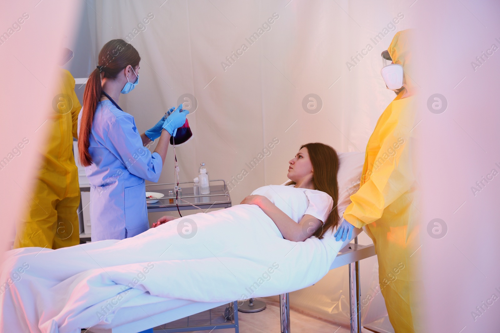 Photo of Professional paramedics examining patient with virus in quarantine ward