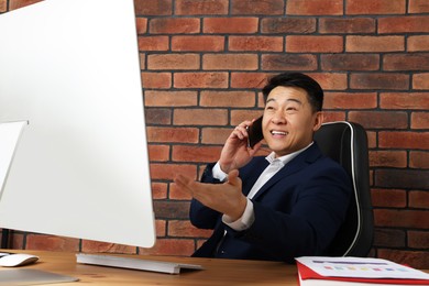 Happy boss talking on phone in his office
