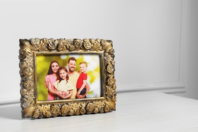 Photo of Framed family photo on white wooden table indoors, space for text