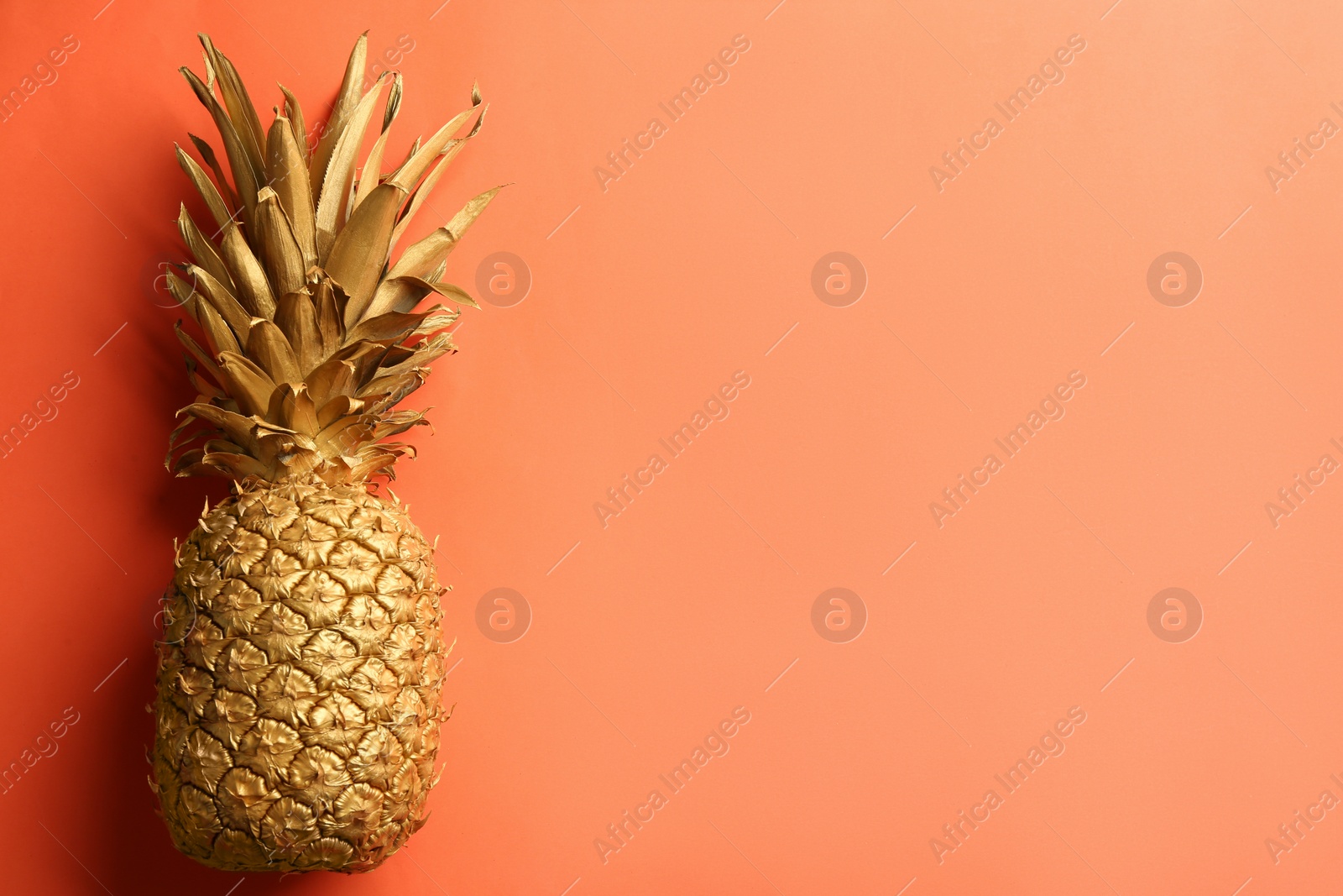 Photo of Golden pineapple on orange background, top view with space for text. Creative concept