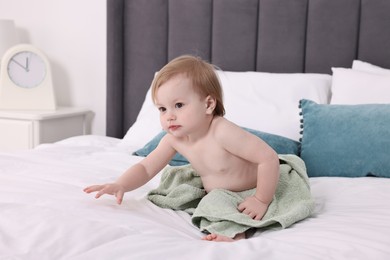 Cute little baby with towel after bathing on bed