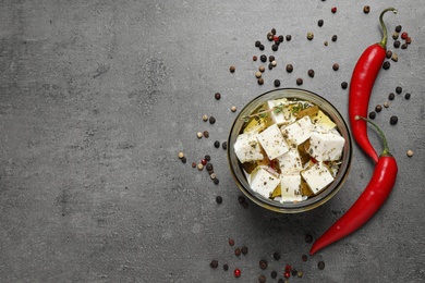 Flat lay composition with feta cheese marinated in oil on grey table, space for text. Pickled food