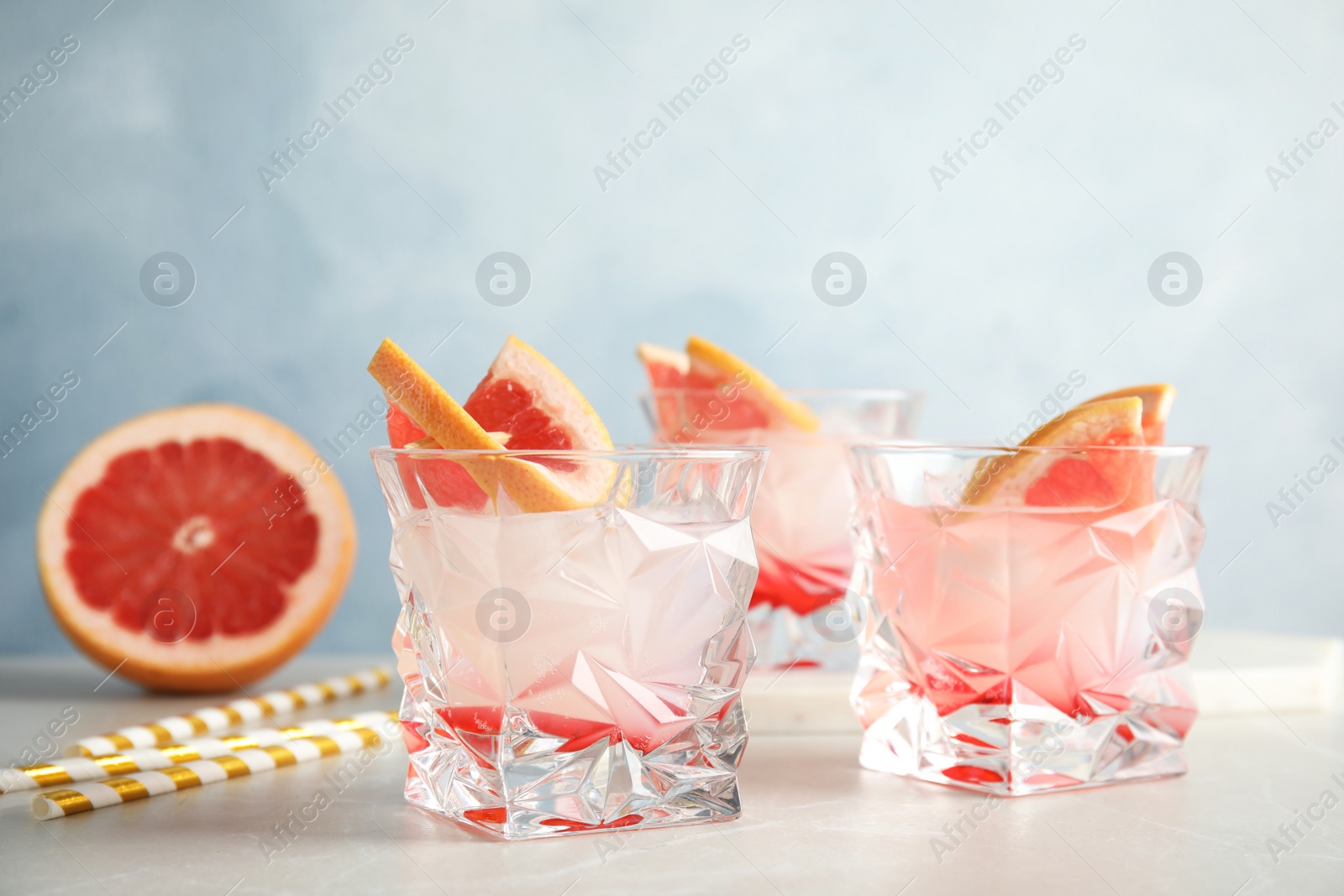 Photo of Glasses with tasty grapefruit cocktails on table