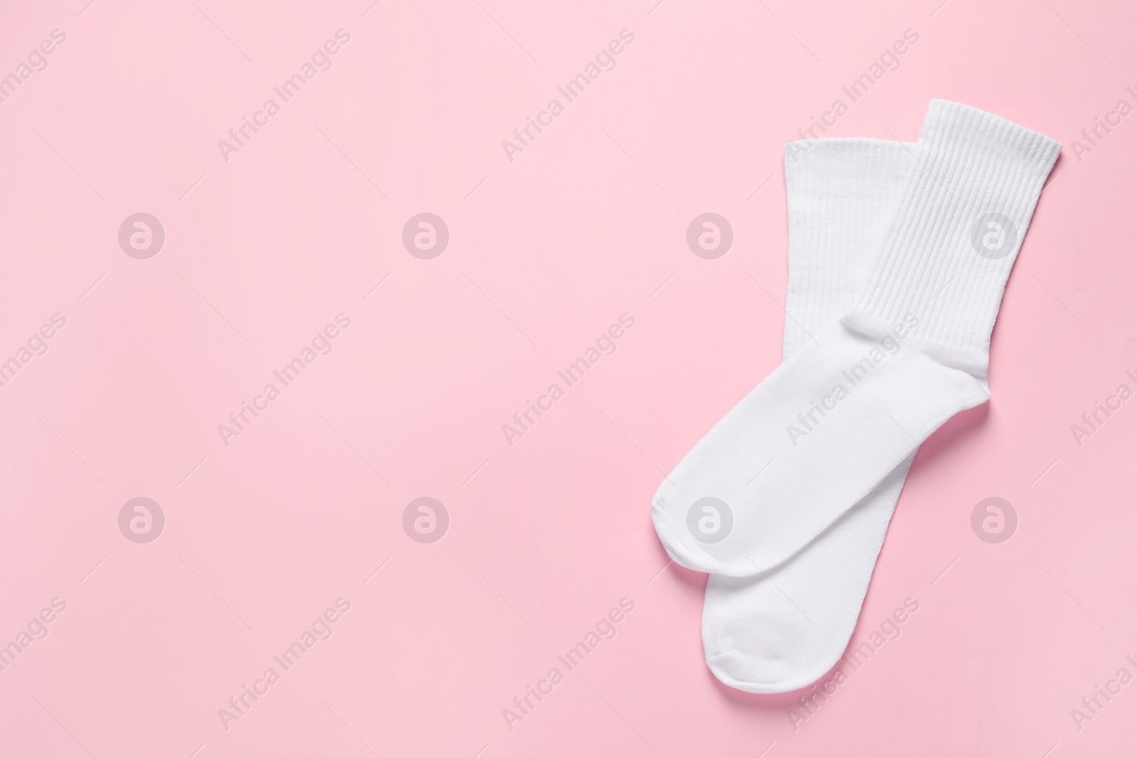 Photo of Pair of white socks on pink background, flat lay. Space for text