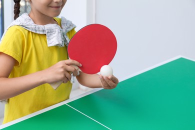 Little girl playing ping pong indoors, closeup