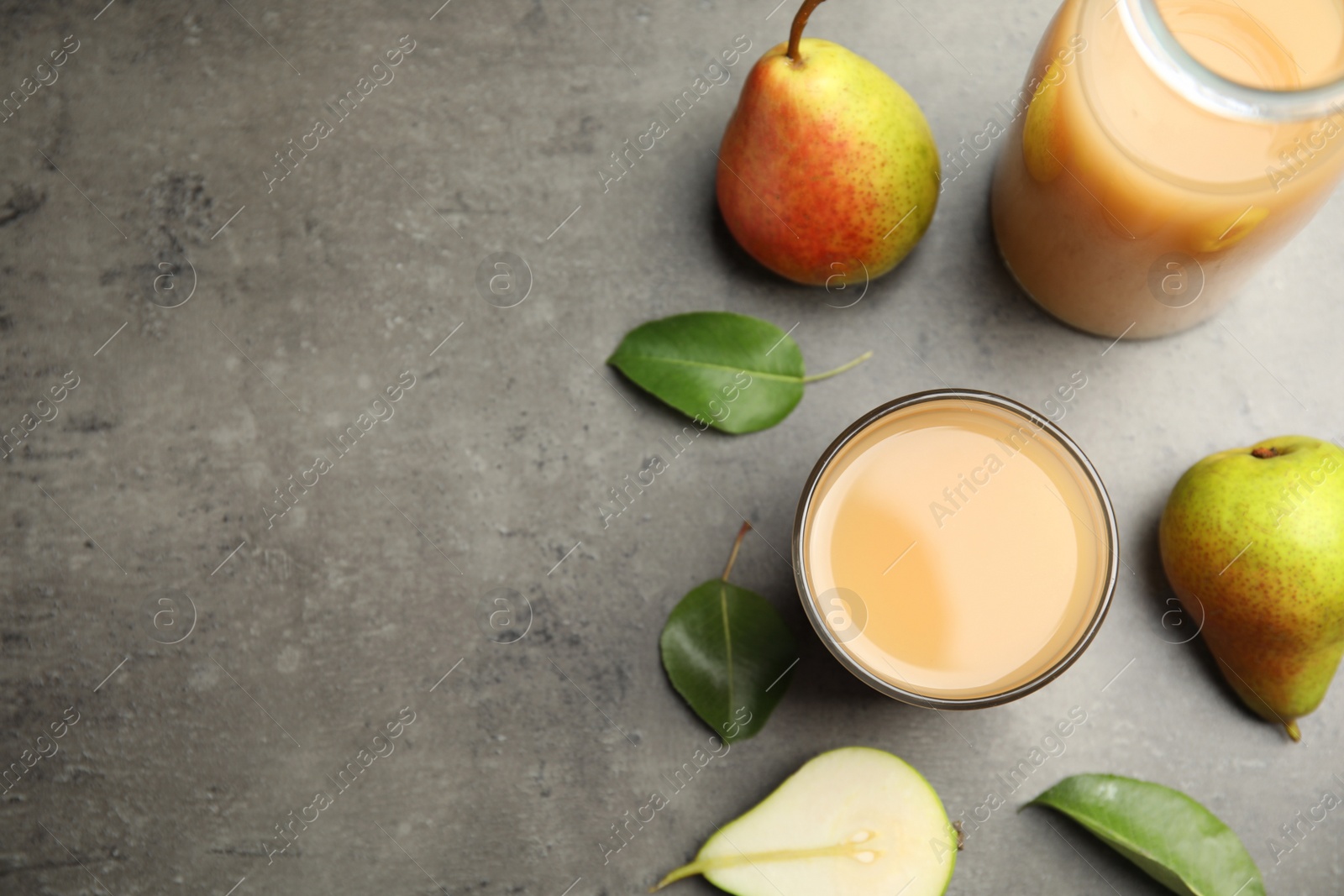 Photo of Tasty pear juice, fruits and leaves on grey table, flat lay. Space for text