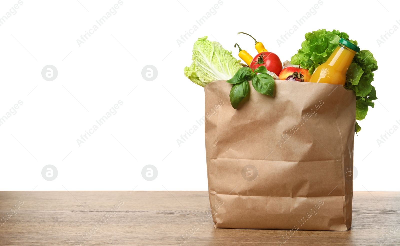 Photo of Paper bag with vegetables and bottle of juice on table against white background. Space for text