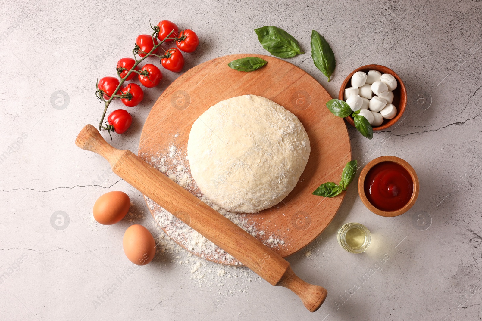 Photo of Pizza dough, products and rolling pin on gray textured table, flat lay