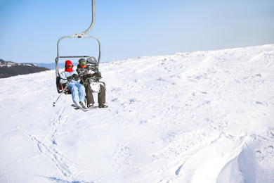 Photo of People using chairlift at mountain ski resort, space for text. Winter vacation
