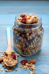 Jar of tasty granola with nuts and dry fruits on light blue wooden table