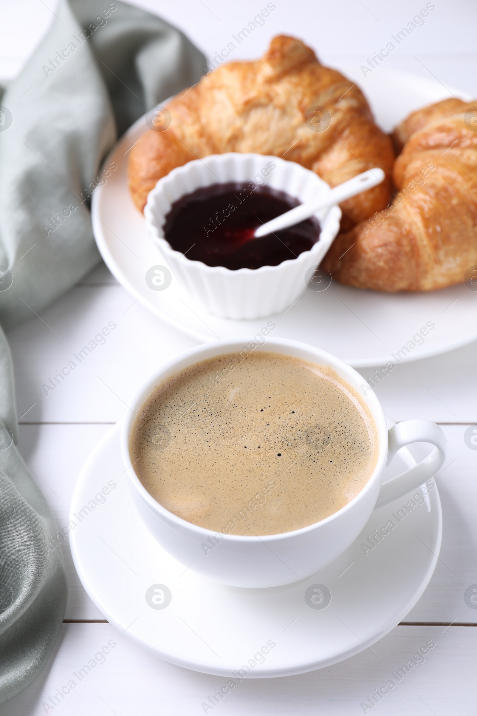 Photo of Fresh croissants, jam and coffee on white wooden table. Tasty breakfast