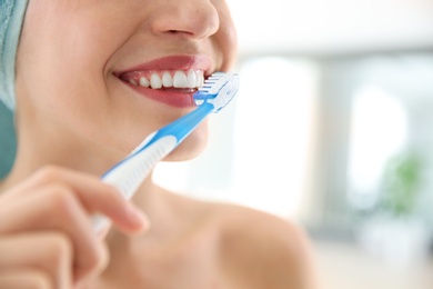 Photo of Young woman with toothbrush on blurred background, closeup. Space for text