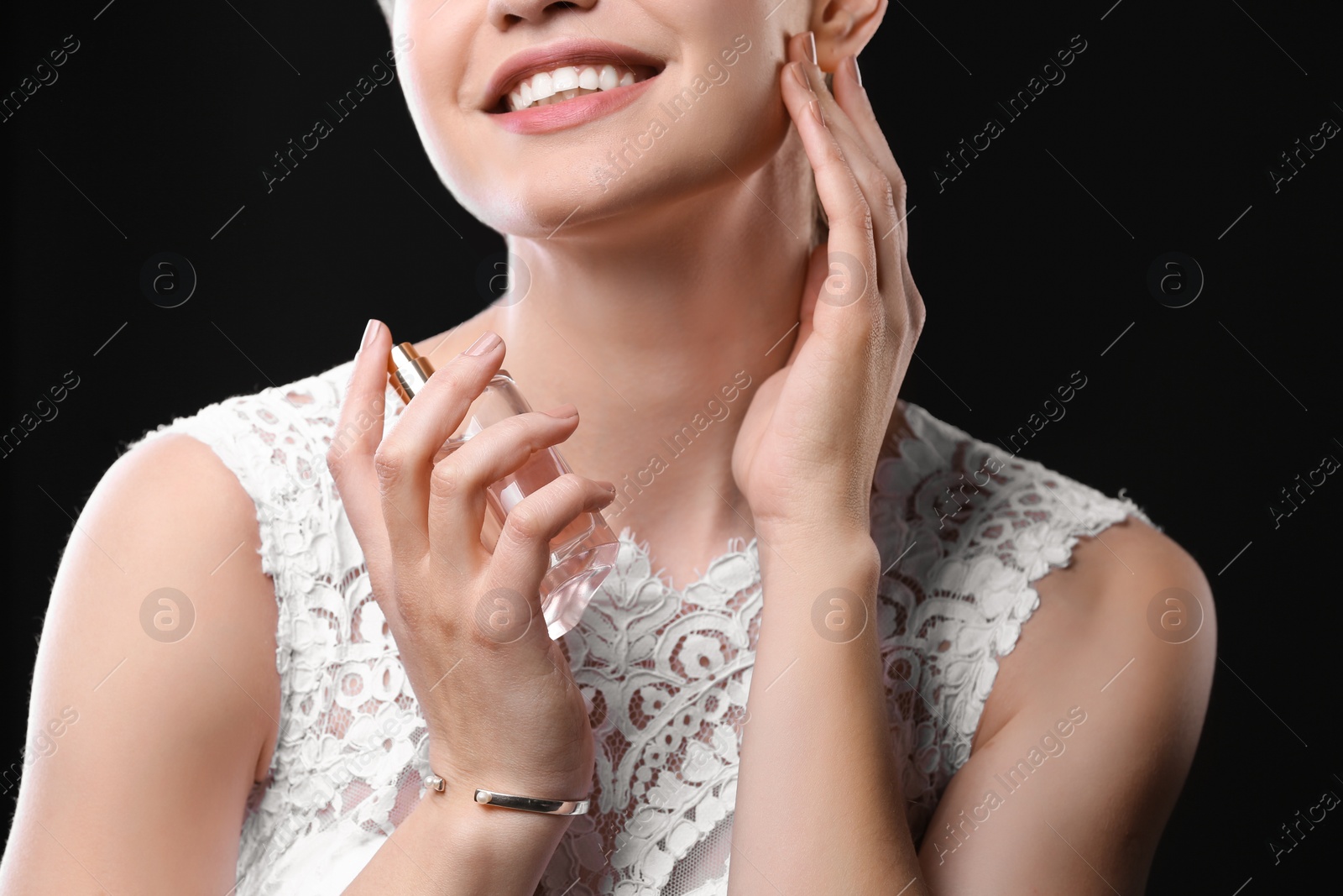 Photo of Beautiful young bride with bottle of perfume on black background, closeup