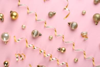 Shiny serpentine streamers and Christmas balls on pink background, flat lay